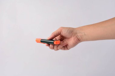 El, beyaz arka planda turuncu bir işaret tutuyor.