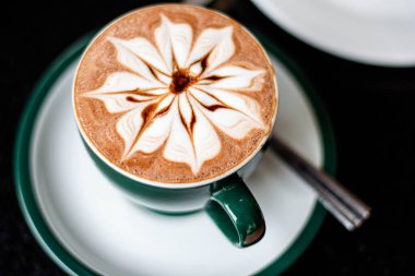 Yeşil fincanda sıcak çikolata ve pasta.