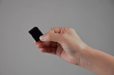 Hafıza kartını tutan kişi gri arkaplanda izole edildi