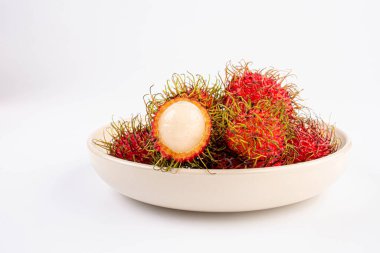 Beyaz masa zemininde seramik beyaz tabakta Rambutan meyvesi.