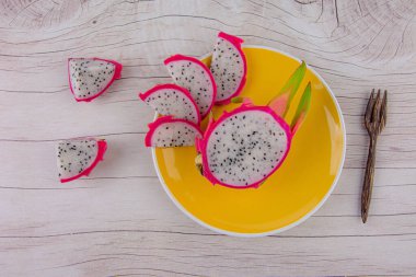 Dragon fruit and wooden spoon isolated on wood background