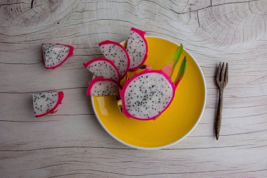 Dragon fruit and wooden spoon isolated on wood background