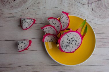 Dragon fruit and wooden spoon isolated on wood background