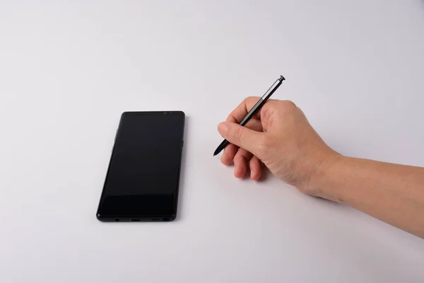 Hand and smartphone and black stylus for writing isolated on white background.