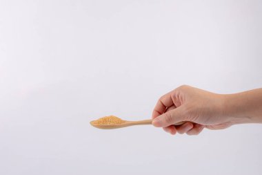 Kahverengi şeker beyaz arka planda tahta kaşıkta.