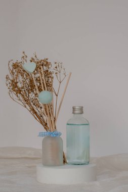 Aroma yayıcı parfümlü sıvı ve beyaz masadaki kamış çubukları için..