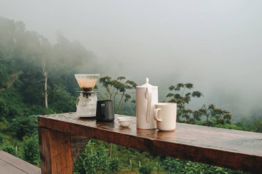 Arka planda dağ manzaralı ahşap masaya damlatılmış kahve seti