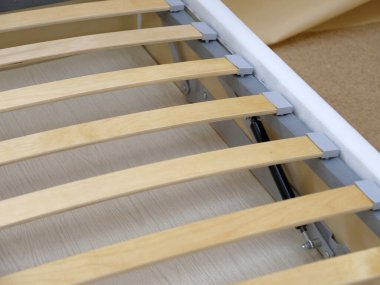 Üretim. Yatak beyaz kumaşla döşenmiş, şilteli yok. Tahta levhalar.