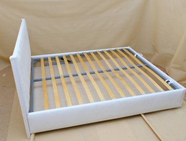 Üretim. Yatak beyaz kumaşla döşenmiş, şilteli yok. Tahta levhalar.