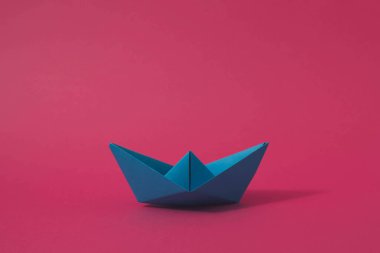 Blue origami paper boat on pink background. Minimal concept. clipart
