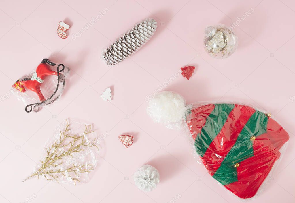 Christmas ornaments wrapped in plastic foil on a pale pink background. Minimal concept.