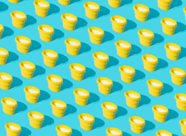 Mavi arka planda beyaz sütle dolu sarı boya kovalarının deseni. Asgari konsept.