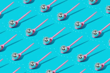 Mavi arka planda pembe plastik kaşıklarda parlak sikso toplarından yapılmış desen. Parti deseni.