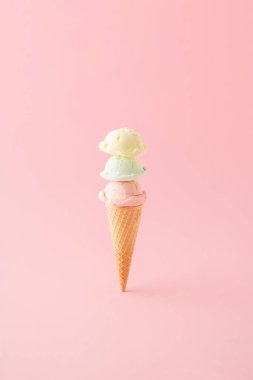Pembe arka plana dikey yerleştirilmiş külahta üç kepçe dondurma. Asgari yaz konsepti.