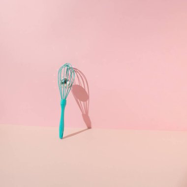 Turkuaz yumurta çırpıcı, elle krema çırpma çırpma ve pembe arka plana yaslanmış disko topu. Asgari konsept.