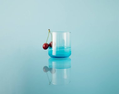 Mavi arka planda taze kirazlı bardak içmek. Ayna yansıması.