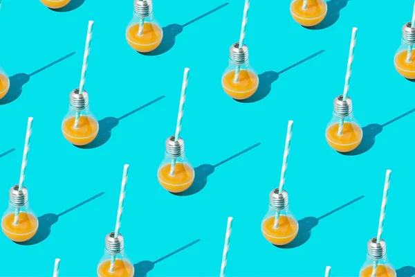 Energy pattern with orange juice drink in light bulb with striped drinking straw on blue background.