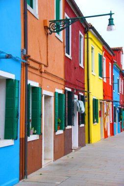 Close-up of facade of small houses of various bright colors. In the background the clear blue sky. Picturesque street image with colorful houses. Typical urban image of the city of murano in venice