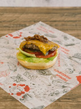 Çizmesiz peynirli burger, karamsar soğanlı ve tepside ekmek ve ahşap masa yok.