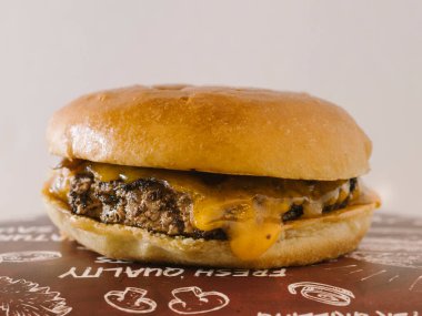 Kırmızı tepside tek peynirli burger ve karamsar soğan.