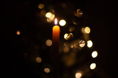 Işıkların arka planında yanan bir mum.