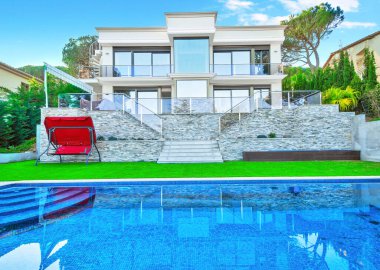 Yüzme havuzu ve oturma alanı olan lüks bir villa. Güzel çimleri olan modern bir ev.. 