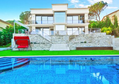 Yüzme havuzu ve oturma alanı olan lüks bir villa. Güzel çimleri olan modern bir ev.. 