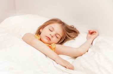 Yatak odasında battaniyenin altında uyuyan tatlı kız. Yatakta yatarken. Uyanış konsepti ve uyku zamanı. Bir instagram filtresi ile yakın plan portresi.