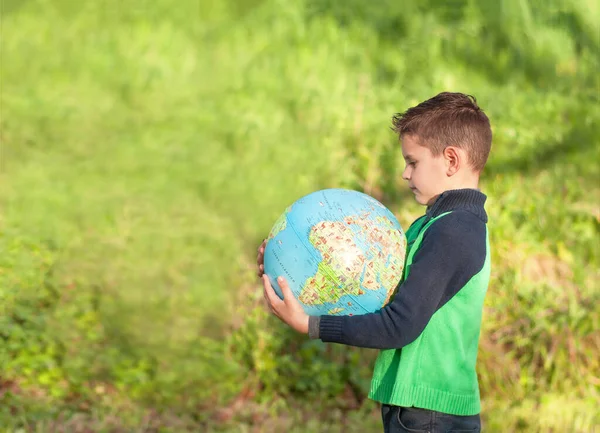ハンサムな男の子が地球を握っている 公園の中の人形 世界の地図を勉強する — ストック写真