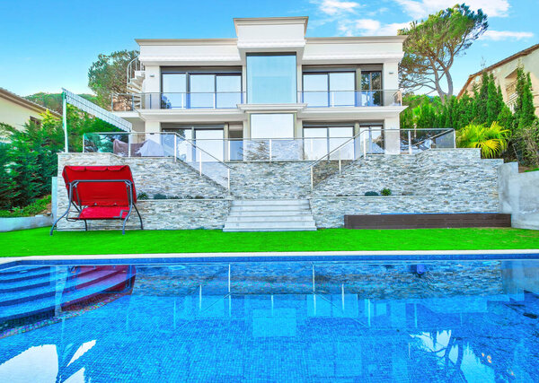 Luxurious villa with a swimming pool and with a seating area. Modern house with a beautiful lawn. 