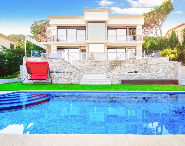 Yüzme havuzu ve oturma alanı olan lüks bir villa. Güzel çimleri olan modern bir ev.. 