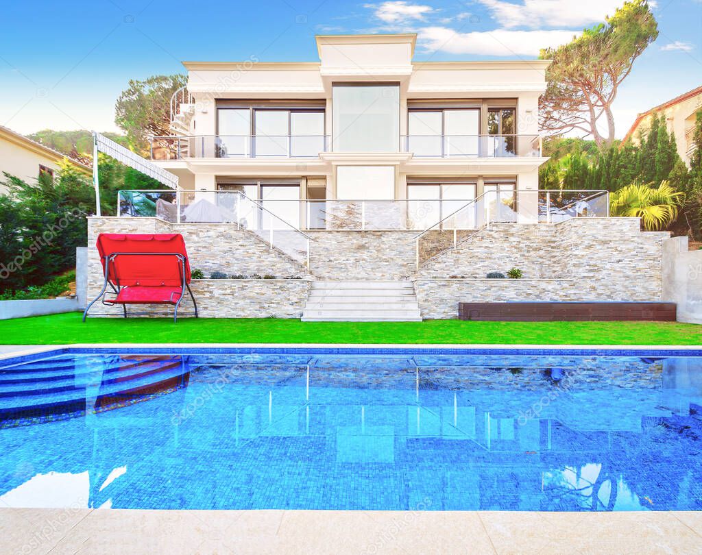 Luxurious villa with a swimming pool and with a seating area. Modern house with a beautiful lawn. 