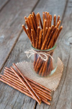 Bardaktaki tuzlu çubuklar ve ahşap masa, seçici bir odak ile. 