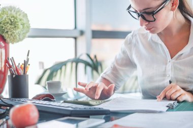 Ofis çalışanı. Finans, vergi, muhasebe, istatistik ve analitik araştırma konseptini hesaplamak için hesap makinesi ve dizüstü bilgisayar kullanan genç iş kadını. 