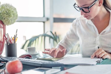 Ofis çalışanı. Finans, vergi, muhasebe, istatistik ve analitik araştırma konseptini hesaplamak için hesap makinesi ve dizüstü bilgisayar kullanan genç iş kadını. 