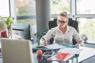 Ofis sandalyesinde oturan ve sözleşmeleri ve belgeleri kontrol eden bir kız. Ofis çalışanı. İş kadını.