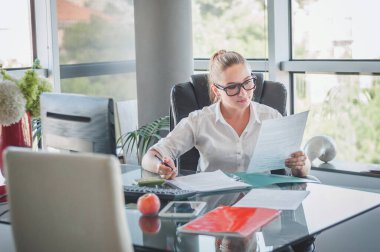 Ofis sandalyesinde oturan ve sözleşmeleri ve belgeleri kontrol eden bir kız. Ofis çalışanı. İş kadını.