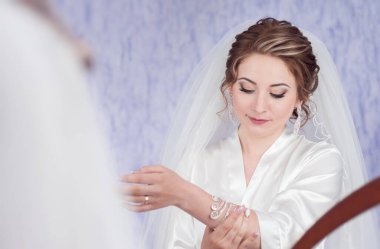 Gelinin sabahı. Gelin şu anda aynaya bakıyor. Güzel ve genç bir gelinin portresi. Bilezik takıyor..