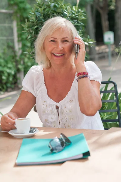 Leende Mogen Kvinna Pratar Smartphone Och Dricker Kaffe Caféet Pensionerad Royaltyfria Stockfoton