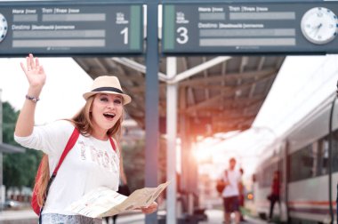 Harita, şapka ve sırt çantalı gezgin kız tren istasyonunda yürüyor.. 