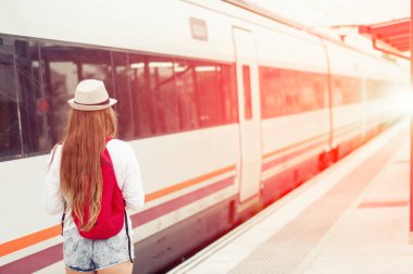 Tren istasyonunda haritalı, şapkalı ve sırt çantalı gezgin kız.. 