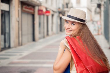 Şapkalı ve alışveriş torbalarıyla şehirde alışveriş yapan tatlı bir kız. Metin için boş alanı olan yakın plan portresi. Avrupa 'da alışveriş. 