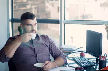 Düşünceli sakallı iş adamı mola veriyor, işyerinde kahve içiyor. Bir fincan taze kahveden esinlenilmiştir. 