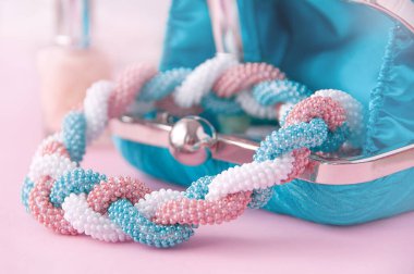 Kadın aksesuarları: bilezik, oje, kolye, pembe arka plan. Moda kadınsı geçmişini kapat. El yapımı boncuklu kolye ve bilezik. Güzellik günlüğü konsepti.
