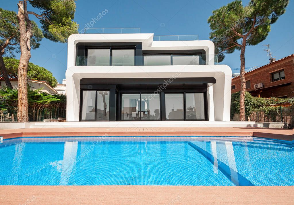 Luxurious villa with swimming pool at dusk. External view of a contemporary house. New technologies in construction.