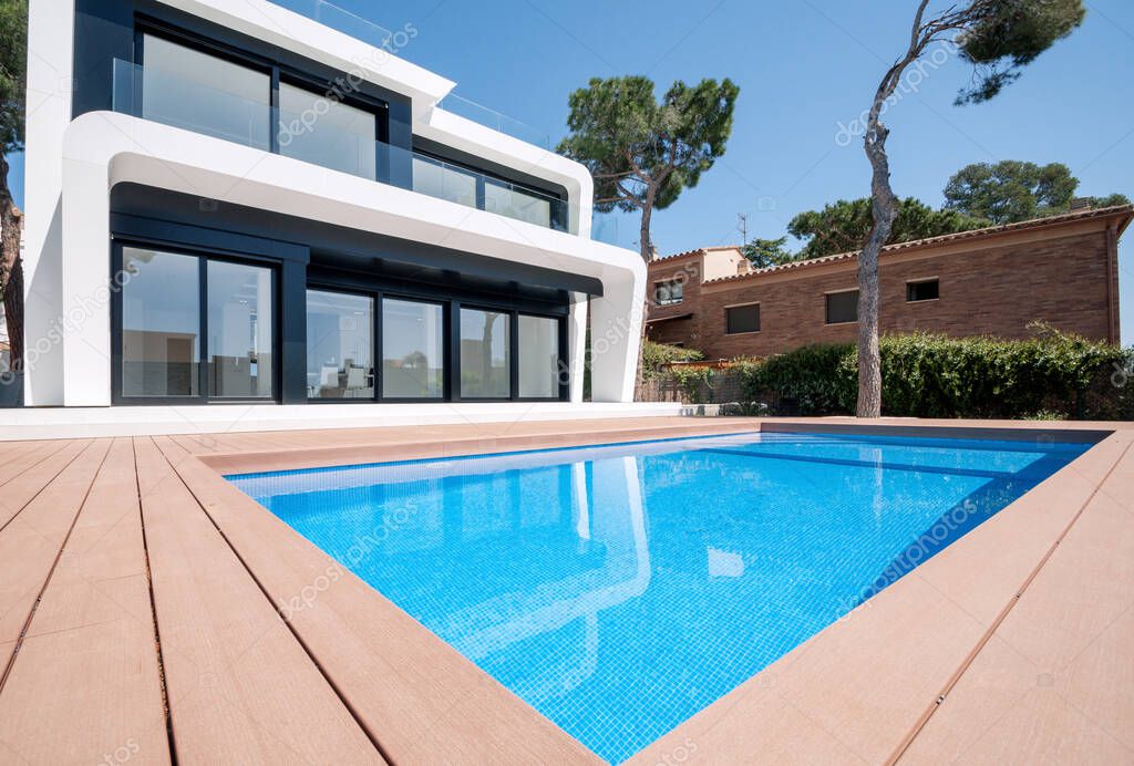 Luxurious villa with swimming pool at dusk. External view of a contemporary house. New technologies in construction.