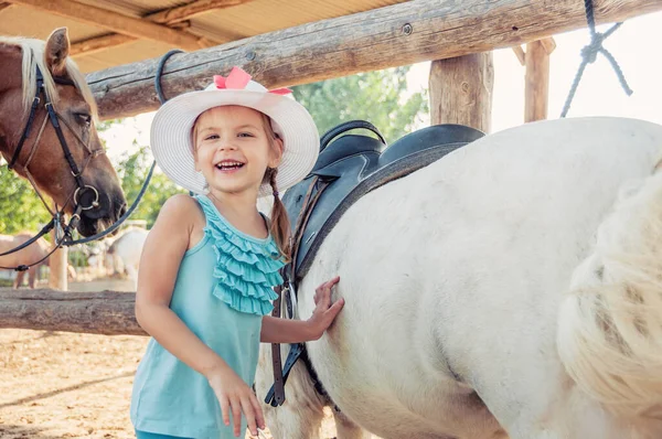 小さな陽気な女の子と馬 帽子をかぶった女の子 — ストック写真