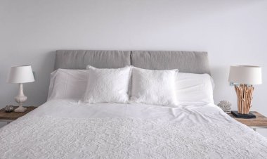 Uyku yatağında dantelli beyaz yastıklar. Rahat yumuşak yastıklar ve dekoratif lambalar.. 