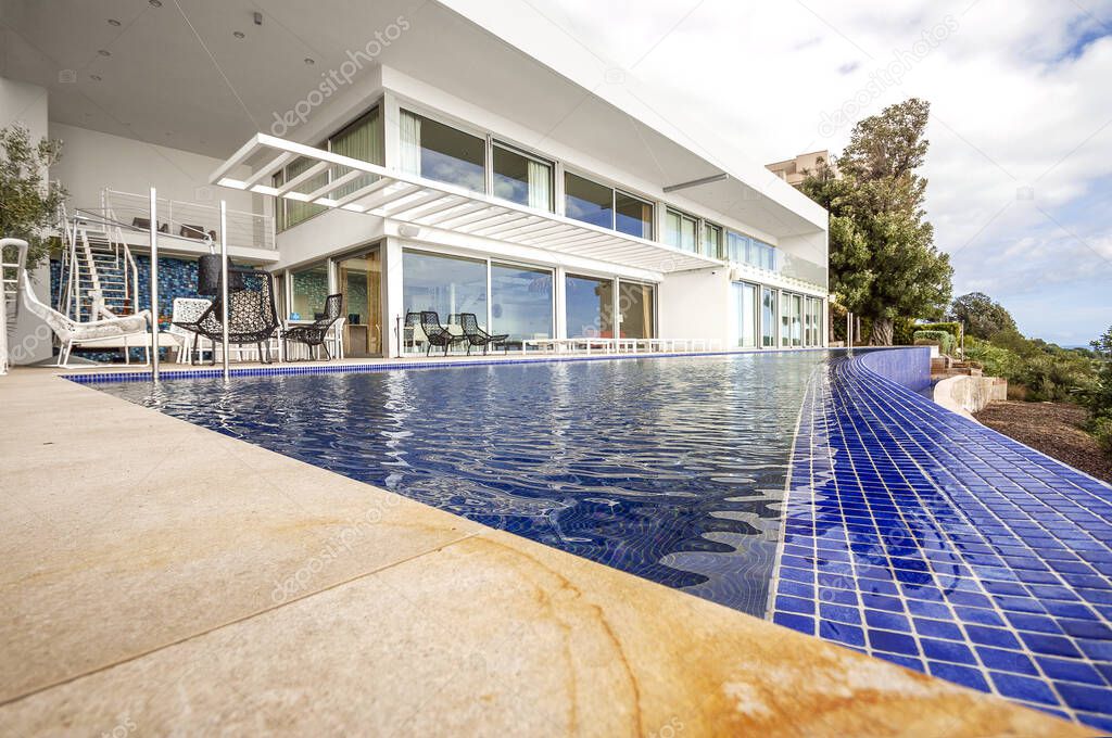 Luxury white double storey villa facade and luxury infinity pool. 