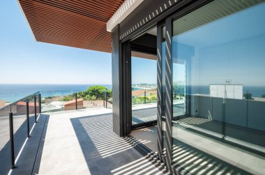 Cam bölmeli büyük bir terastan deniz manzarası.